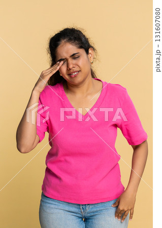 Indian woman emotionally covers face with hands showing sadness, looking sadly through fingers Indian woman emotionally covers face with hands showing sadness, looking sadly through fingers 131607080
