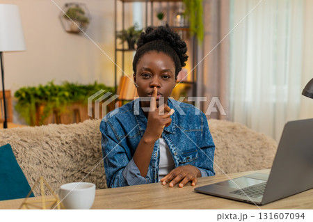 African American young woman shows silence secret gesture with finger to lips hinting secret at home African American young woman shows silence secret gesture with finger to lips hinting secret at home 131607094