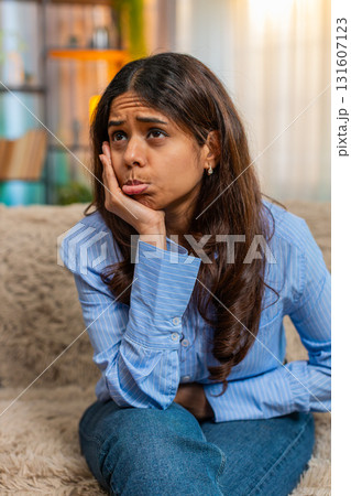 Indian woman feeling heartbroken after breakup with sad emotional face and low energy on home sofa 131607123