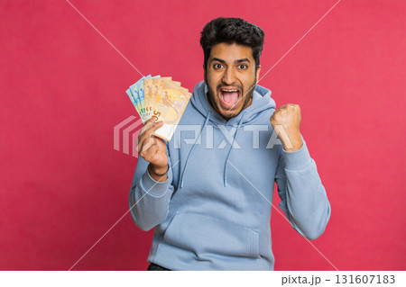 Happy Indian young man holding euro cash counting money showing profit salary or bank loan success Happy Indian young man holding euro cash counting money showing profit salary or bank loan success 131607183