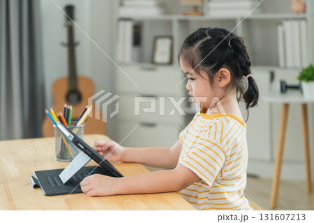 Young girl engaged in online learning at home, using tablet with focused expression, bright room with natural light, creative workspace atmosphere Young girl engaged in online learning at home, using tablet with focused expression, bright room with natural light, creative workspace atmosphere 131607213