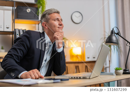 Handsome young businessman thinking business ideas while sitting with laptop at home office desk 131607299