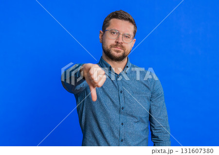 Upset man guy showing thumbs down gesture disapproval dissatisfied dislike negative feedback 131607380