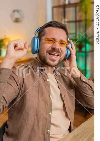 Happy Caucasian man in headphones and sunglasses dancing listening to music at home office desk Happy Caucasian man in headphones and sunglasses dancing listening to music at home office desk 131607425