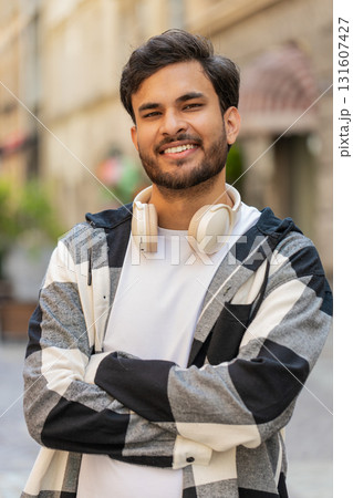 Smiling Indian young man smiling at camera, resting, relaxation feel satisfied in city street 131607427