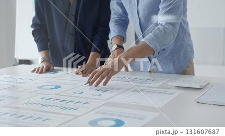 Business professionals analyzing financial charts, gesturing over spreadsheets during collaborative meeting in contemporary workspace, discussing data driven insights Business professionals analyzing financial charts, gesturing over spreadsheets during collaborative meeting in contemporary workspace, discussing data driven insights 131607687