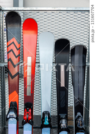 New modern luxury premium red black white skis selection stored vertically in metal rack at alpine shop or rental at mountain ski resort winter season. Sport hobby equipment gear. Active lifestyle 131607704