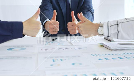 Business team showing thumbs up sign in meeting celebrating success with financial charts, data analysis, sales growth reports, and teamwork achievement in modern office Business team showing thumbs up sign in meeting celebrating success with financial charts, data analysis, sales growth reports, and teamwork achievement in modern office 131607736