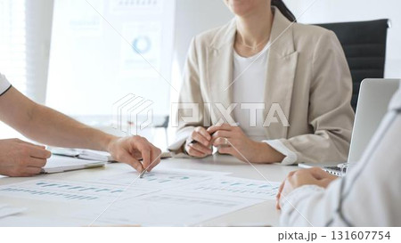 Business team analyzing financial data and discussing marketing strategy during a meeting in the office, businesswoman pointing at charts and explaining strategy to colleagues Business team analyzing financial data and discussing marketing strategy during a meeting in the office, businesswoman pointing at charts and explaining strategy to colleagues 131607754