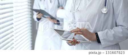Medical professional using a digital tablet for patient care and data management, collaborating with doctors and healthcare workers in a modern clinic or hospital setting 131607823