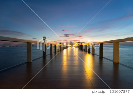Walkway extending into calm sea at twilight. 131607877
