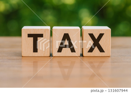Wooden cubes spelling the word TAX on a smooth reflective surface with a blurred green background Wooden cubes spelling the word TAX on a smooth reflective surface with a blurred green background 131607944