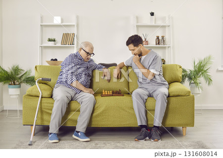 Young nurse man playing chess game with senior elderly at home. Young nurse man playing chess game with senior elderly at home. 131608014