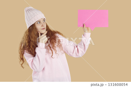 Beautiful teenage girl is thoughtfully looking at empty speech bubble in her hand. Beautiful teenage girl is thoughtfully looking at empty speech bubble in her hand. 131608054