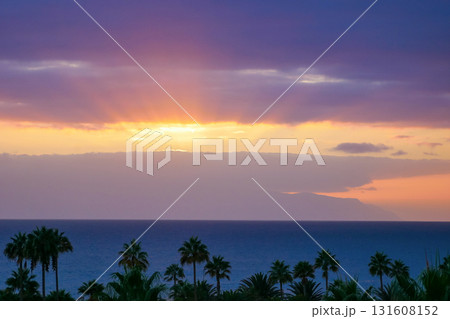 Purple Sunset Over La Gomera island. View from Tenerife with Dramatic Clouds and Silhouetted Palms Purple Sunset Over La Gomera island. View from Tenerife with Dramatic Clouds and Silhouetted Palms 131608152