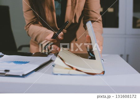 Close-up of businessman's hands making notes, mobiles, chart, desk, office 131608172