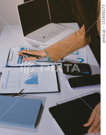 Close-up of businessman's hands making notes, mobiles, chart, desk, office Close-up of businessman's hands making notes, mobiles, chart, desk, office 131608173