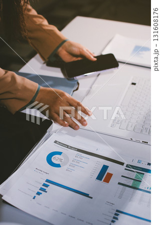 Close-up of businessman's hands making notes, mobiles, chart, desk, office 131608176