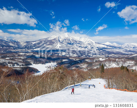 青空の下でスキーを楽しむ人々と遠くに見える妙高山の眺望 (長野県、斑尾高原) 131608831