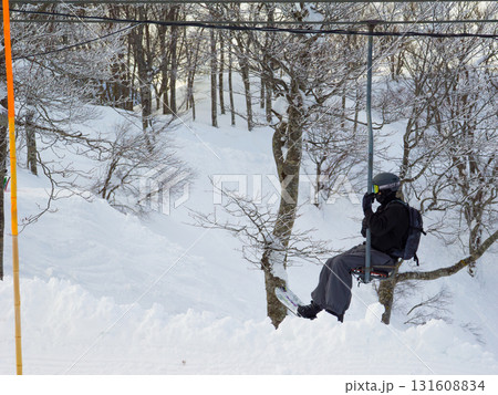 雪の林を背景に山頂へ向かうシングルリフトとスノーボーダー (新潟県、斑尾高原) 131608834