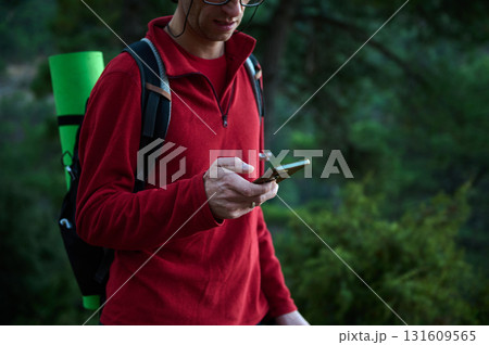 Hiker in Red Jacket Using Smartphone Outdoors With Backpack on Forest Trail 131609565