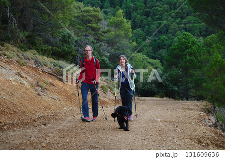 Hiking Couple With Dog On Rustic Trail Through Green Forest Hiking Couple With Dog On Rustic Trail Through Green Forest 131609636