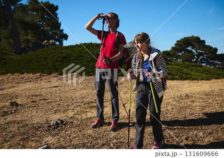 Two Hikers With Trekking Poles Exploring a Sunny Trail Together on an Outdoor Adventure 131609666