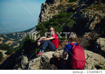Hikers Rest On Mountain Ridge With Backpack And Trekking Poles Hikers Rest On Mountain Ridge With Backpack And Trekking Poles 131609671