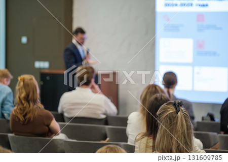 Business conference with speaker presenting to attentive audience in modern conference room Business conference with speaker presenting to attentive audience in modern conference room 131609785