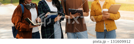 Happy students walking together on university campus, chatting and laughing outdoors after classes 131609912