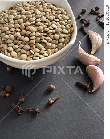 Lentils in white bowl on a black surface. Healthy, wholesome, plant-based food. 131610019