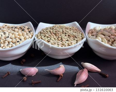 White beans, lentils, and black-eyed peas in white bowls on a black surface. Healthy, wholesome, plant-based food. White beans, lentils, and black-eyed peas in white bowls on a black surface. Healthy, wholesome, plant-based food. 131610063