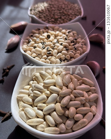 White beans, lentils, and black-eyed peas in white bowls on a black surface. Healthy, wholesome, plant-based food. 131610067