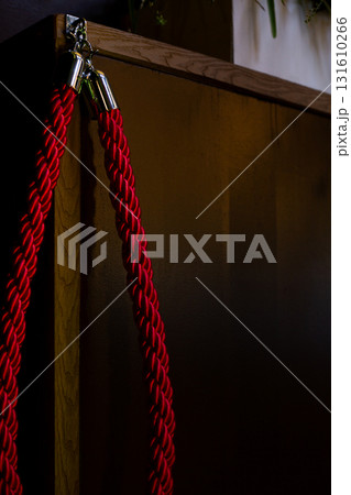 Vibrant red rope elegantly draped over wooden corner, bathed in soft light that highlights its texture and contrasts with dark background, invoking sense of boldness and sophistication Vibrant red rope elegantly draped over wooden corner, bathed in soft light that highlights its texture and contrasts with dark background, invoking sense of boldness and sophistication 131610266