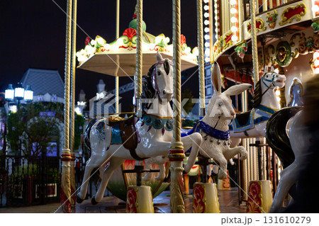 Illuminated carousel ride with colorful horses and rabbit figure, evoking sense of nostalgia and fun. Perfect for children entertainment, and festive events. Creating joyful memories Illuminated carousel ride with colorful horses and rabbit figure, evoking sense of nostalgia and fun. Perfect for children entertainment, and festive events. Creating joyful memories 131610279