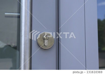 Close-Up Of Modern Glass Door Lock On Light Blue Exterior Metal Frame 131610369