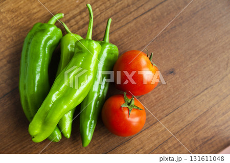 Fresh, tasty organic vegetables, red tomato and green pepper, isolated on brown wood cutting board 131611048