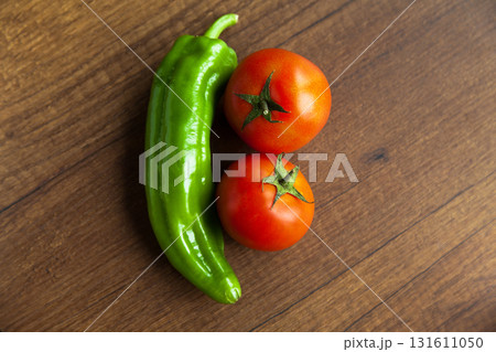 Fresh, tasty organic vegetables, red tomato and green pepper, isolated on brown wood cutting board Fresh, tasty organic vegetables, red tomato and green pepper, isolated on brown wood cutting board 131611050