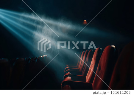 Empty red theater seats illuminated by a bright spotlight through smoke in a dark hall Empty red theater seats illuminated by a bright spotlight through smoke in a dark hall 131611203