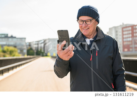 Portrait of senior man using mobile phone while standing on the bridge 131611219
