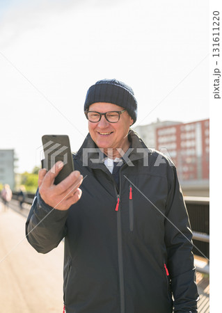 Portrait of senior man using mobile phone while standing on the bridge 131611220