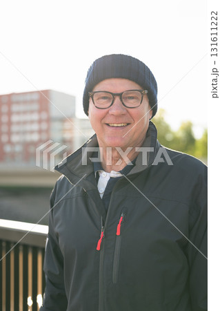 Portrait of a smiling senior man in sportswear on the bridge in Europe 131611222