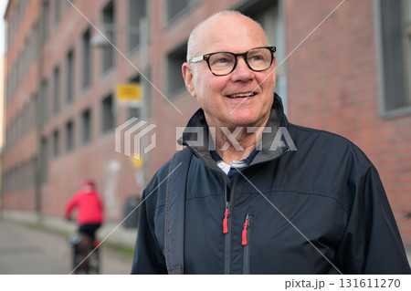 Portrait of a smiling senior man with eyeglasses waiting at a bus stop in the city 131611270