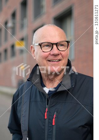 Portrait of a smiling senior man with eyeglasses waiting at a bus stop in the city Portrait of a smiling senior man with eyeglasses waiting at a bus stop in the city 131611271