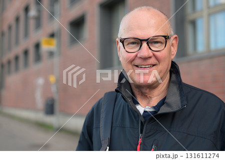 Portrait of a smiling senior man with eyeglasses waiting at a bus stop in the city 131611274
