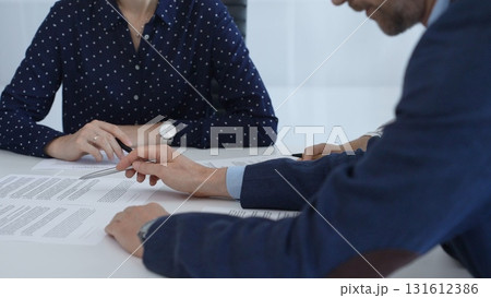 Corporate professionals analyzing contract details, gesturing toward key points while negotiating partnership terms in modern office boardroom 131612386