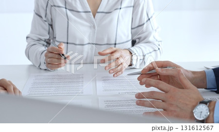 Business professionals or lawyers sitting at the desk in a bright office, reviewing and discussing contract papers. Teamwork concept Business professionals or lawyers sitting at the desk in a bright office, reviewing and discussing contract papers. Teamwork concept 131612567