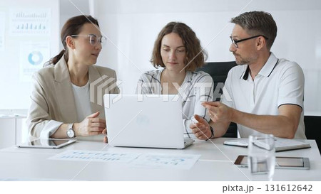 Professional team reviewing project data on laptop, working together in modern office environment, collaborating with focused corporate energy. Business people concept Professional team reviewing project data on laptop, working together in modern office environment, collaborating with focused corporate energy. Business people concept 131612642