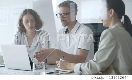 Business team collaborating and analyzing data on a laptop during a productive office meeting, discussing strategies and making informed decisions 131612644