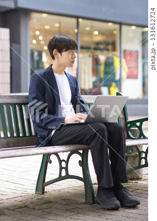 ベンチに座ってパソコン作業をする20代男性 131612724